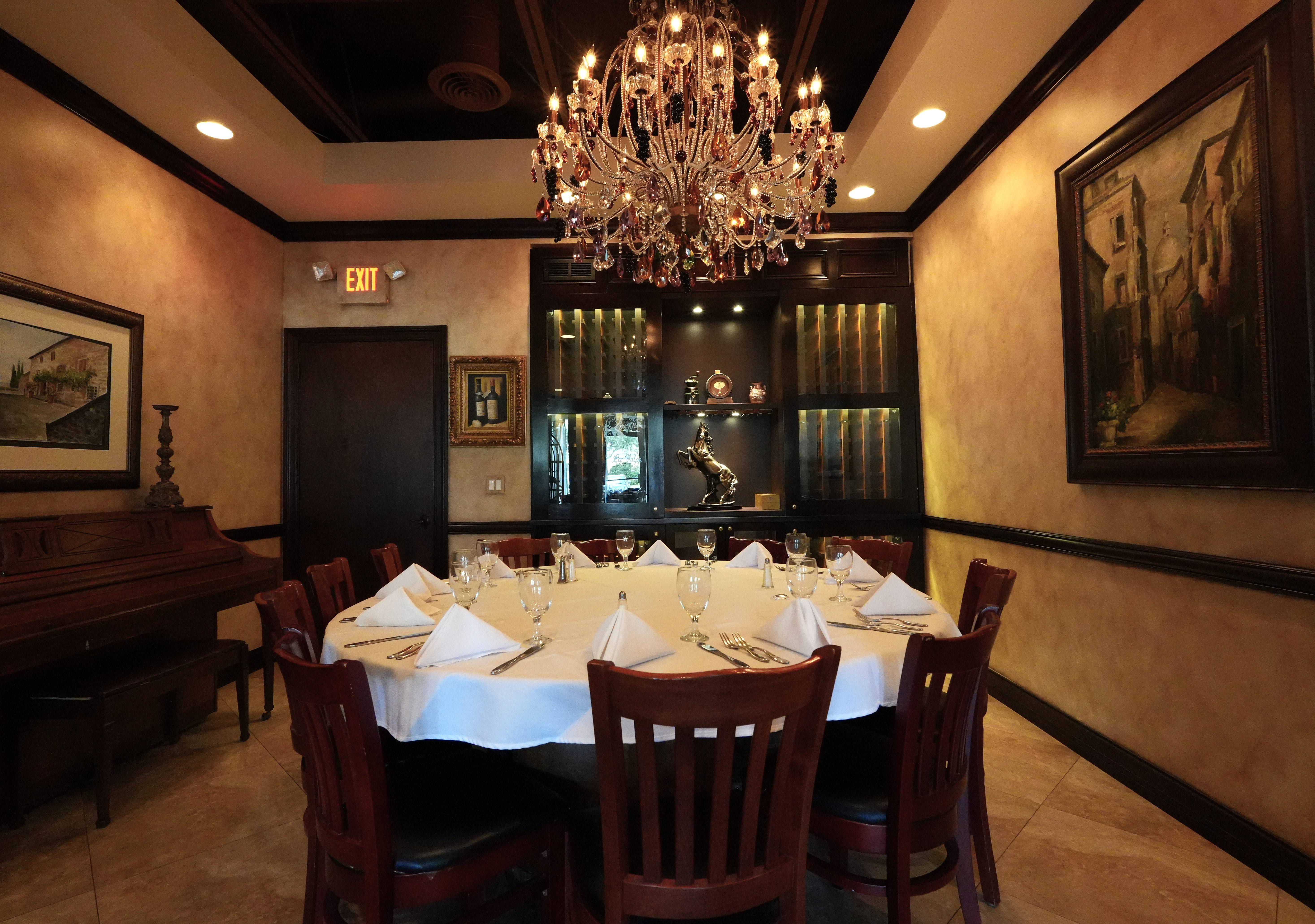 Bella Tavola private dining room with crystal chandelier and round table set for guests