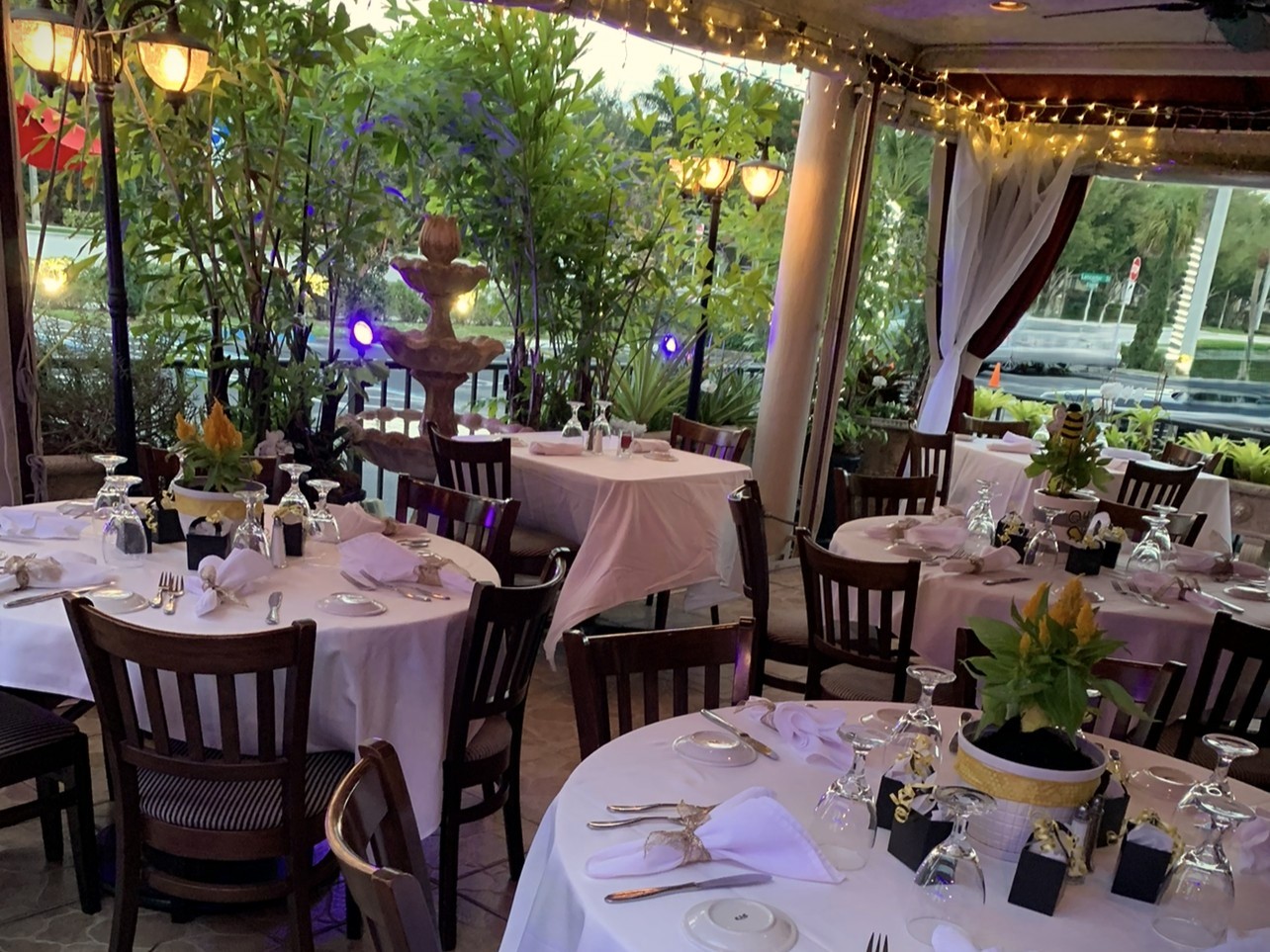 Garden patio with string lights, tropical greenery, and white linen tables